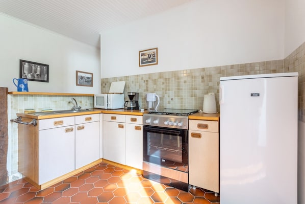 A kitchen with white cabinets, a stove, a sink, and a refrigerator.