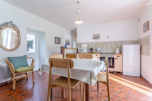 A kitchen with a dining table, chairs, a refrigerator, and a tiled backsplash.