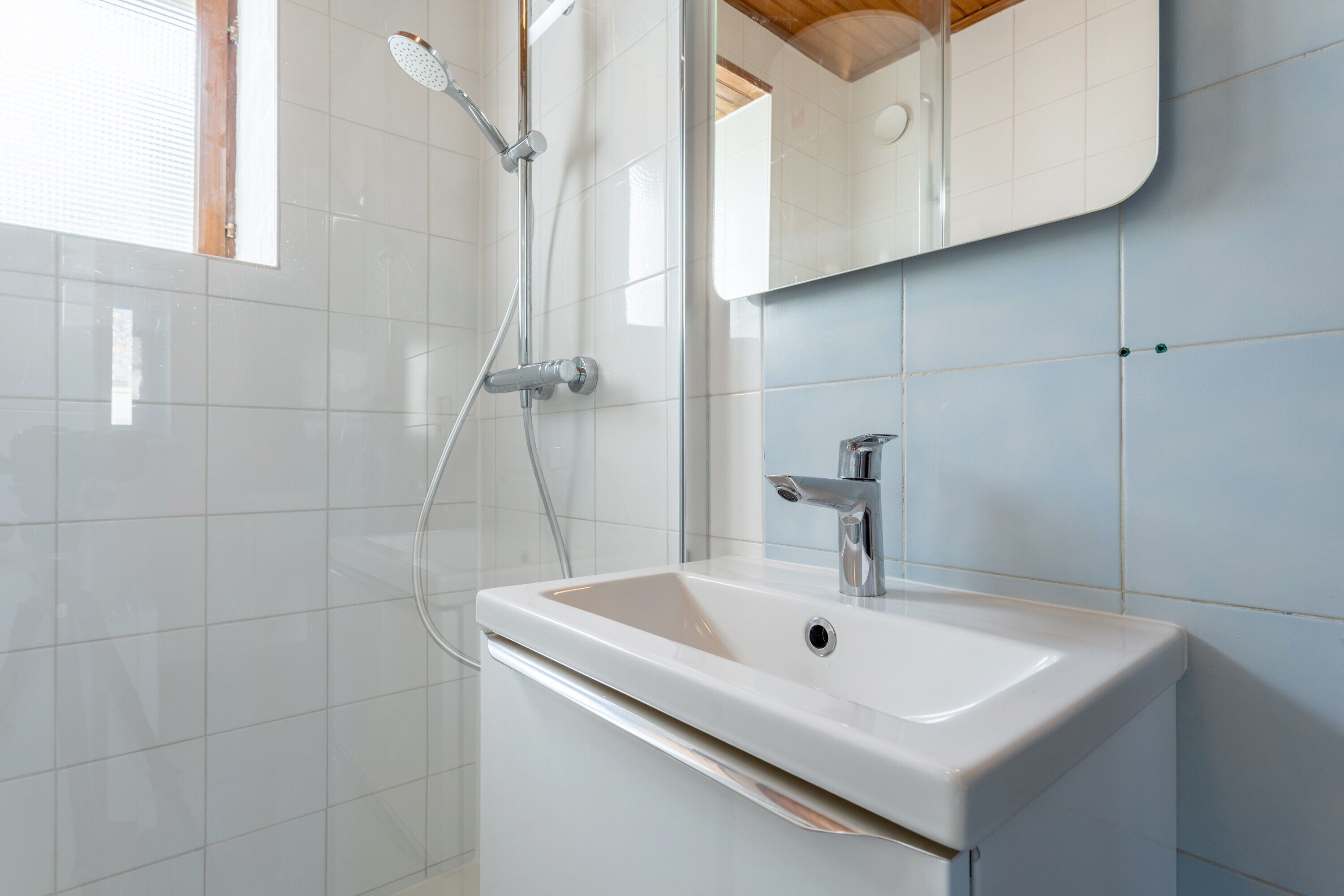 A bathroom with a white sink, a mirror, and a shower.