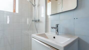 A bathroom with a white sink, a mirror, and a shower.
