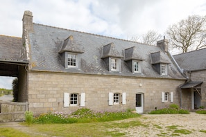 A stone building with multiple windows and a gravel driveway.