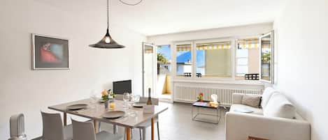 A modern living room with a dining area, a sofa, a coffee table, and a radiator.