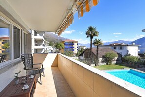 Ein Balkon mit Pool, Esstisch, Stühlen und Blick auf einen Berg.