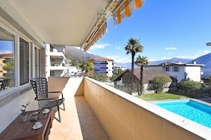 Un balcón con piscina, una mesa de comedor, sillas y vistas a la montaña.