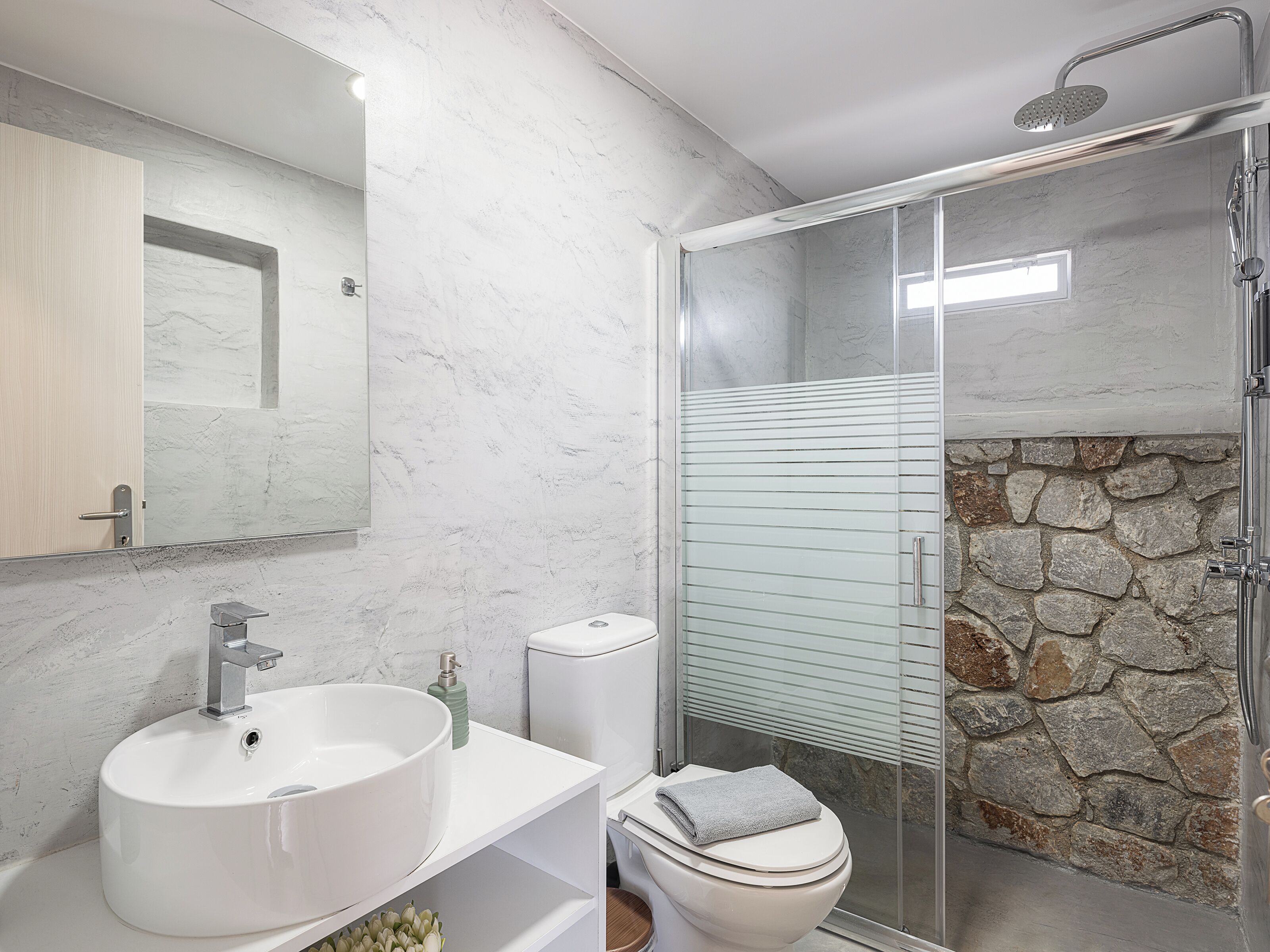A modern bathroom with a white sink, toilet, and shower.