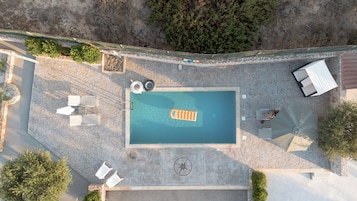 Vista aérea de una piscina con jacuzzi, sillas de descanso y un diseño de brújula en el suelo.