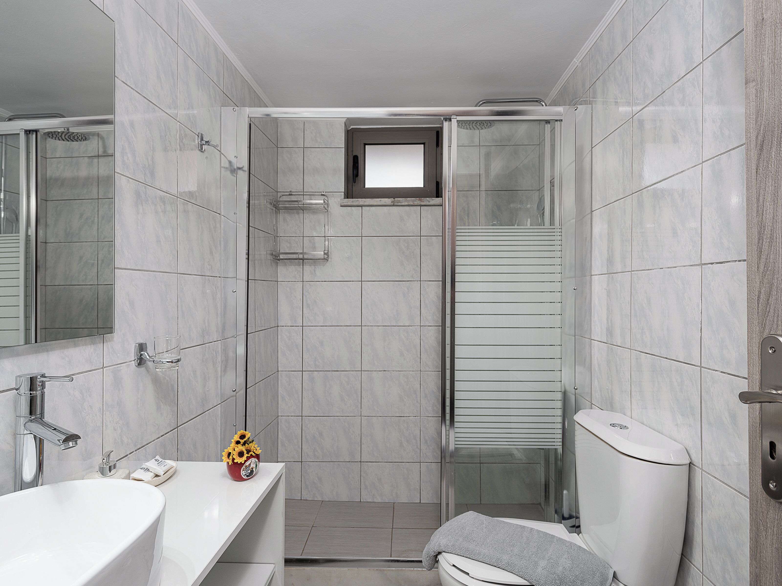 A modern bathroom with a shower, toilet, and sink.