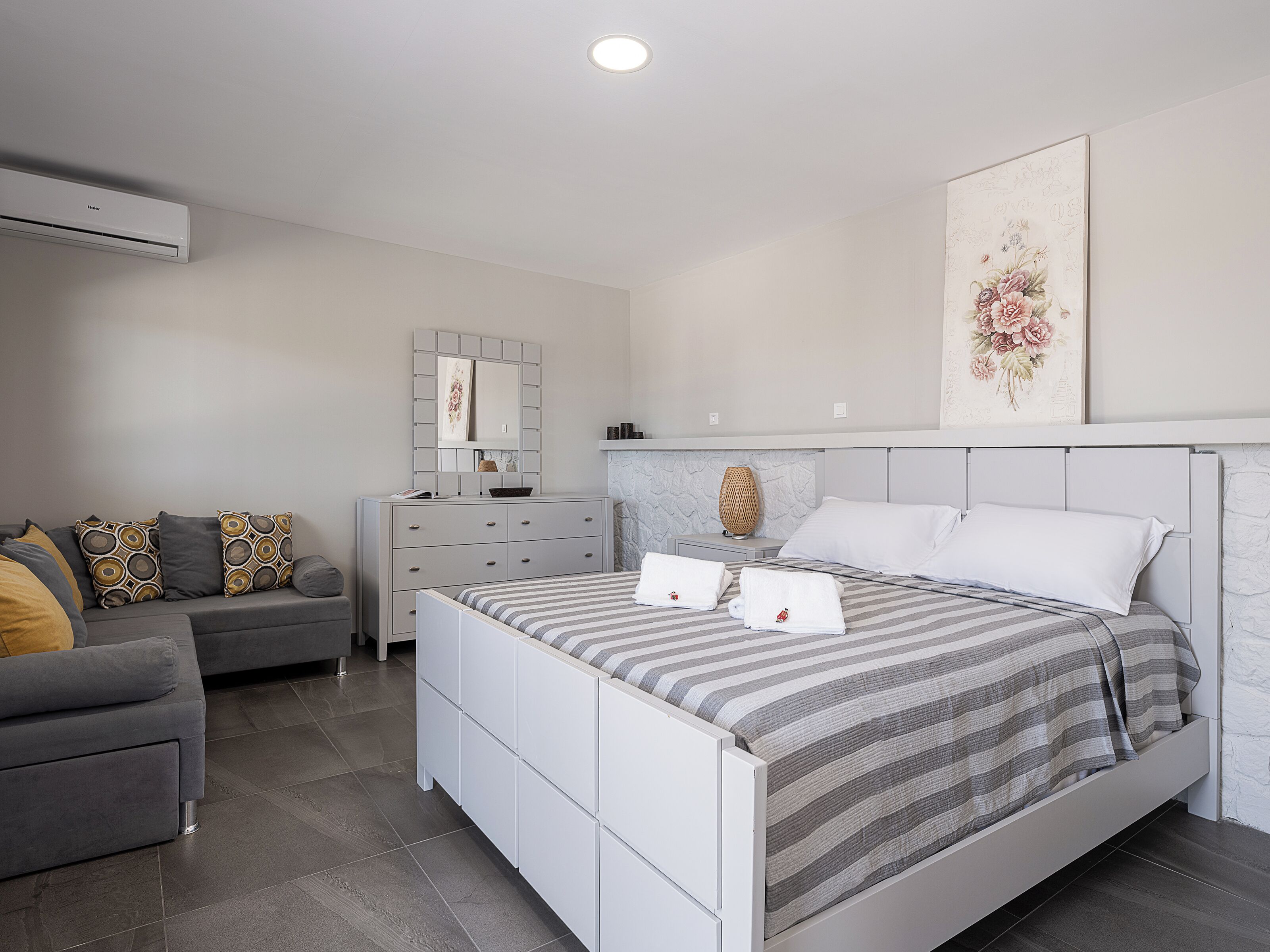 A modern bedroom with a bed, a dresser, a vanity, and a sofa.