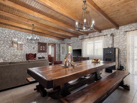 Amplia sala de estar con una gran mesa de madera, paredes de piedra y una chimenea de piedra.