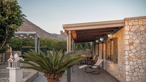 A covered outdoor seating area with stone walls and a pergola structure.