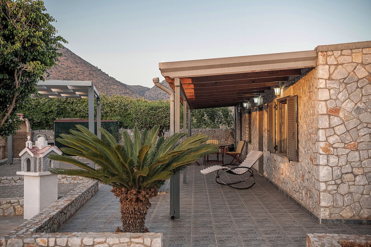 A covered outdoor seating area with stone walls and a pergola structure.