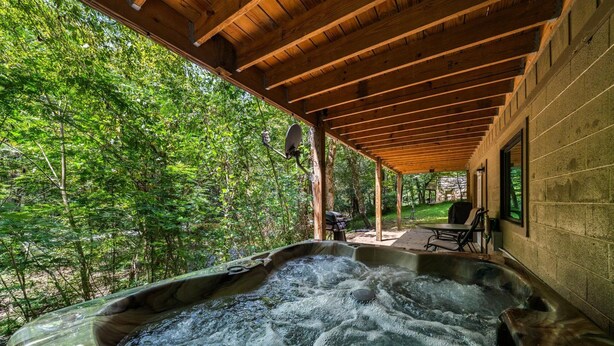 A hot tub under a wooden pergola with a view of a forested area. - On the Rocks: Riverside Relaxation Awaits (Sevierville)