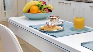 A kitchen counter with a fruit bowl, a croissant, a cup, and a glass of orange juice. - Treasurerome Opera Trevi Green Suite 2BR (Rome)