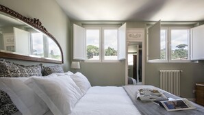 Un lit bien fait, avec du linge de lit blanc et des coussins à motifs, un plateau contenant des articles pour le petit-déjeuner et un magazine posé sur le lit.
