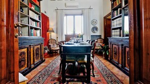 A traditional library with wooden bookshelves, a dining table with chairs, and a patterned rug. - Treasurerome Colosseum Terrace 2BR (Rome)