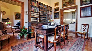 A traditional library with bookshelves, a dining table set for four, and a piano in the background. - Treasurerome Colosseum Terrace 2BR (Rome)