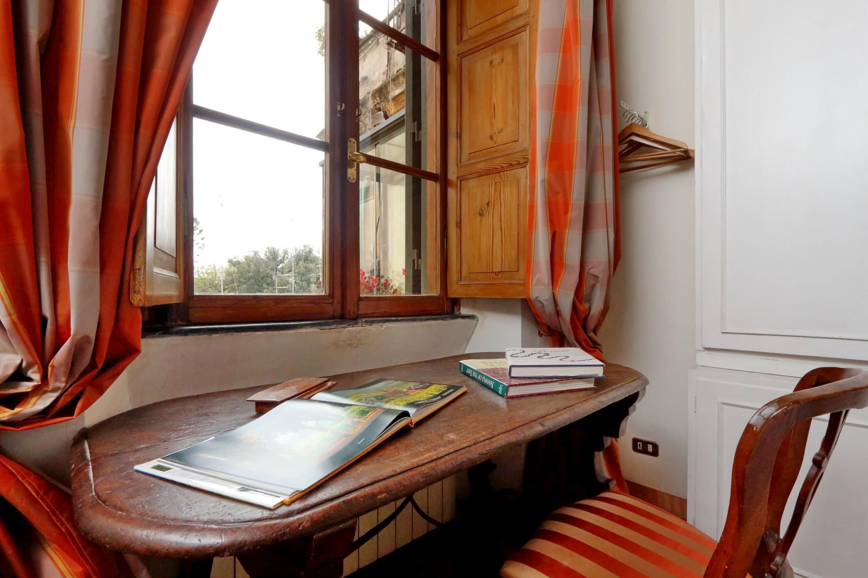 A wooden desk with a chair, a window with curtains, and a wooden cabinet.