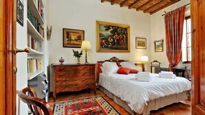 A bedroom with a bed, a dresser, a bookshelf, and a painting on the wall. - Treasurerome Colosseum Terrace 2BR (Rome)