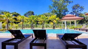 Una piscina al aire libre, sillones reclinables de piscina