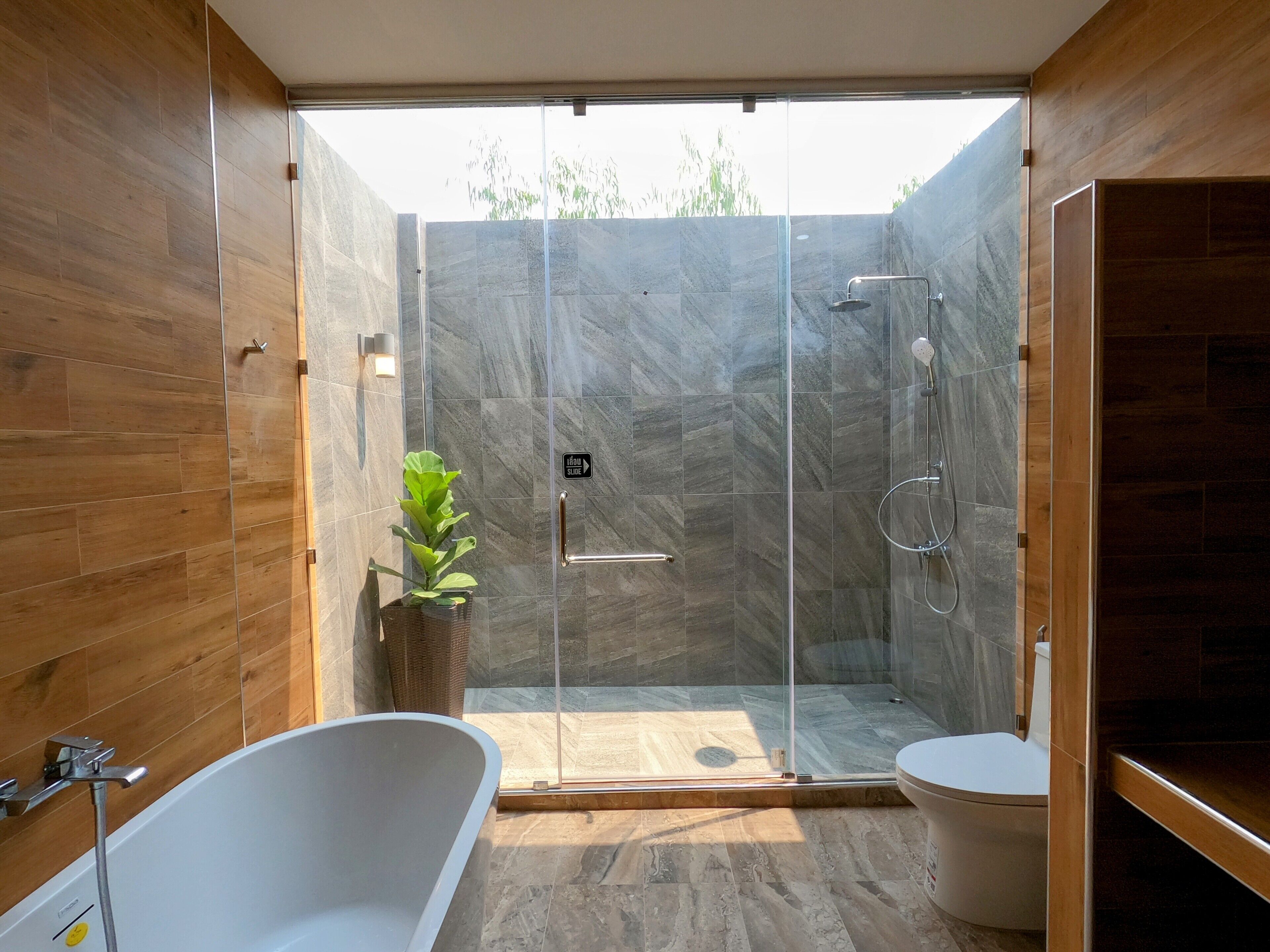 A modern bathroom with a glass-enclosed shower, a freestanding bathtub, and a toilet.