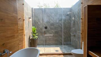 A modern bathroom with a glass-enclosed shower, a freestanding bathtub, and a toilet.