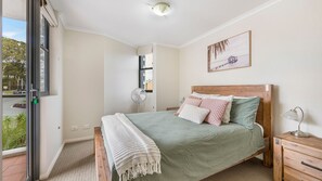 A bedroom with a bed, bedside table, and a window.