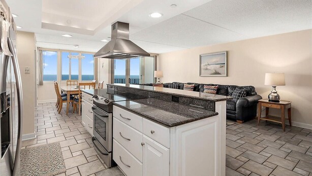 A modern kitchen with a central island, built-in oven, and stainless steel range hood.