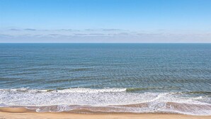 A beach with waves approaching the shore under a clear sky.