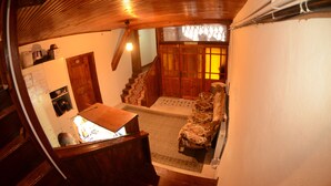 Ein Holzinnenraum mit Treppe, einem Holztisch und einem gemusterten Sessel.