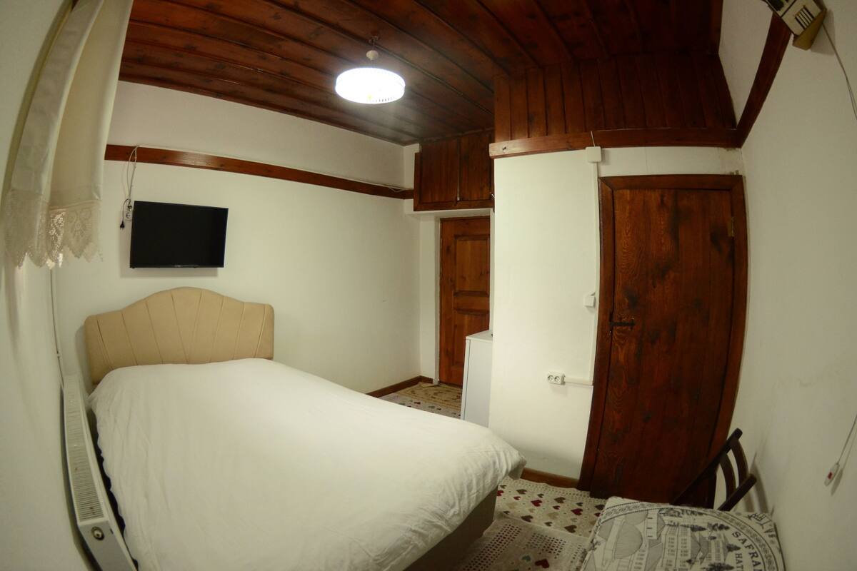 Una camera da letto con un letto, una televisione, una porta in legno e una ventola a soffitto.