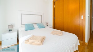A hotel room with a bed, nightstand, lamp, and wooden wardrobe.