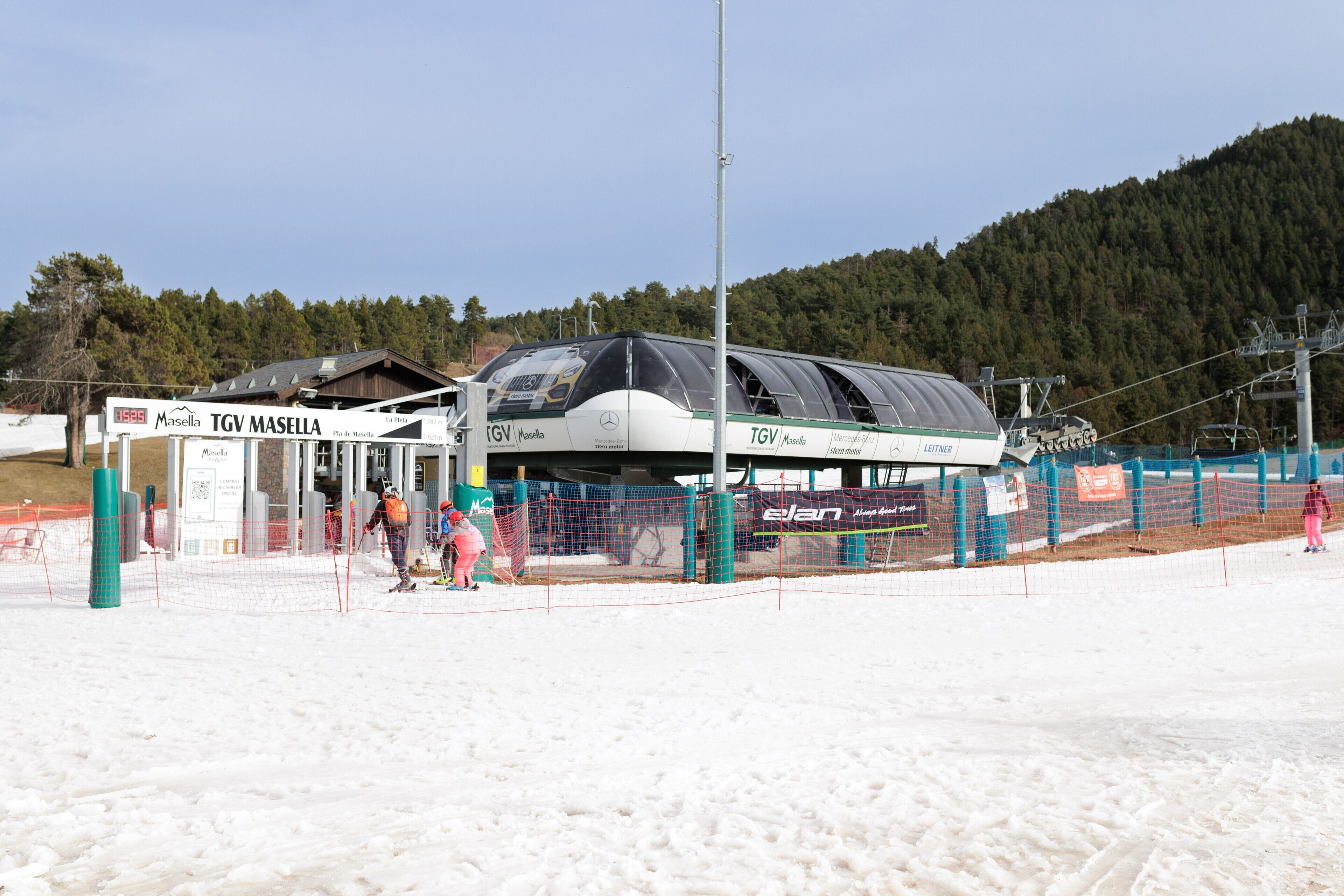 Een liftstation voor skiërs met een beschutte plek, bewegwijzering en een besneeuwd landschap.