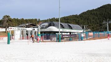Een liftstation voor skiërs met een beschutte plek, bewegwijzering en een besneeuwd landschap.