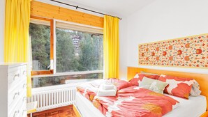 A bedroom with a bed, a radiator, a window with curtains, and a wall with a floral pattern. - Apartment 'Masella' with Mountain View, Shared Garden (Masella)