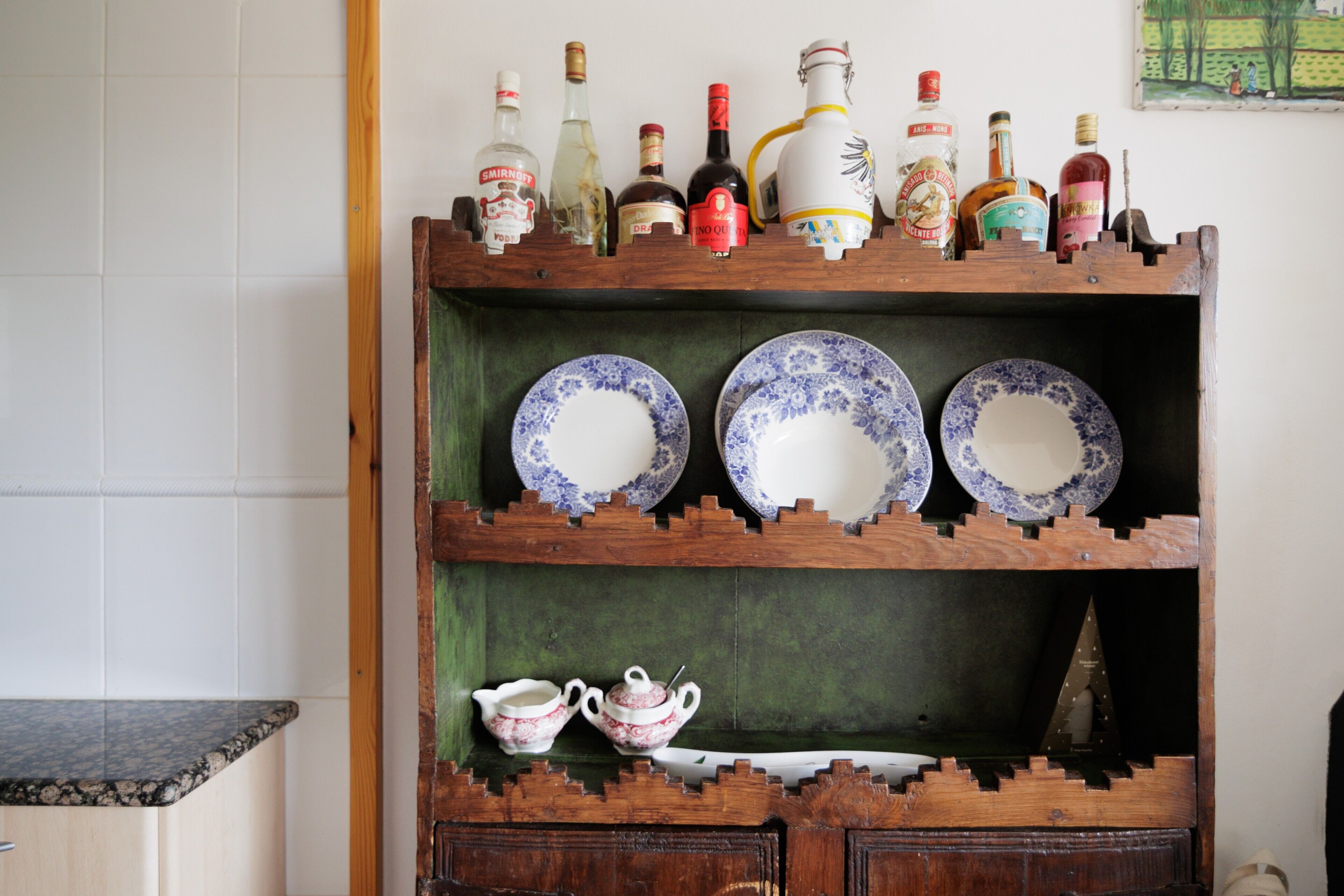 A wooden shelf with various bottles and plates.