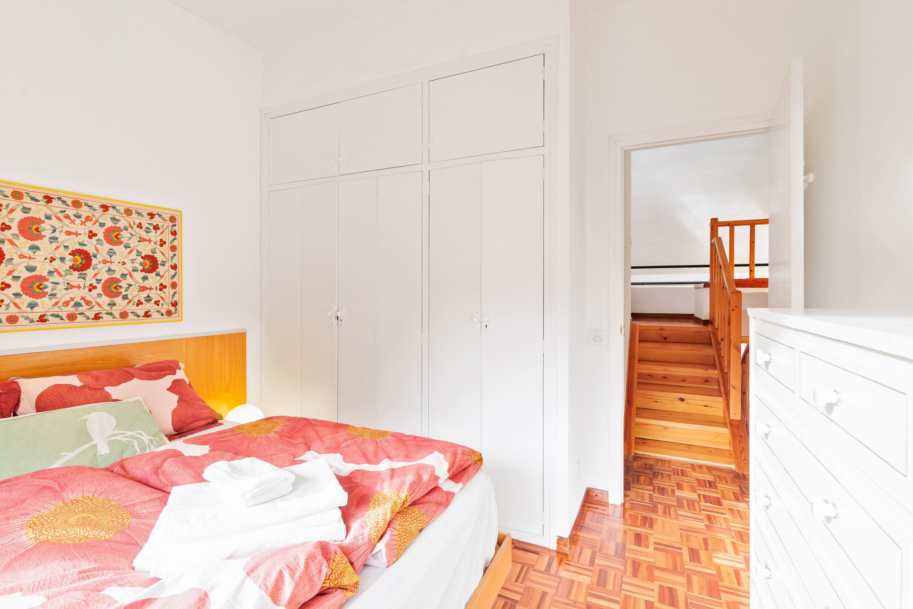A bedroom with a bed, a wardrobe, and a staircase.
