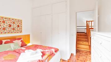 A bedroom with a bed, a wardrobe, and a staircase.