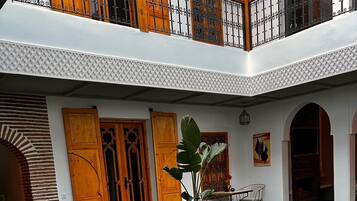 Un patio con piscina, puertas de madera y un comedor.