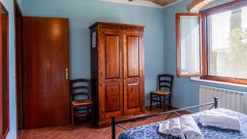 Ein Schlafzimmer mit einem Bett, zwei Stühlen, einem Kleiderschrank und einem Fenster.