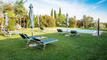 Ein Poolbereich mit Liegestühlen, Sonnenschirmen und einer Schaukel.