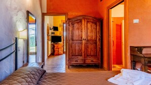 Een slaapkamer met een bed, een houten garderobe en een badkamer die door een open deur zichtbaar is.