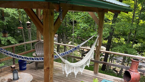 A wooden deck with a hammock, a table with chairs, and a blue chair.