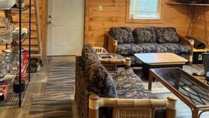 A cozy cabin interior with a sofa, armchair, and a television.