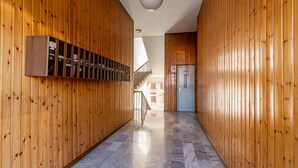 A hallway with wooden paneling and a marble floor, leading to a staircase and a door with a sign. - Casa Carolina (Pavia)