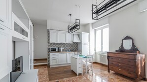 A modern kitchen with white cabinetry, a marble floor, and a wooden dresser with a mirror. - Casa Luigi (Pavia)