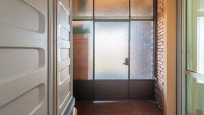 A narrow hallway with a frosted glass door, brick walls, and a tiled floor. - Casa Luigi (Pavia)