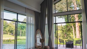 Una habitación amplia con ventanas grandes, piso de madera, una silla redonda y una mesa pequeña.
