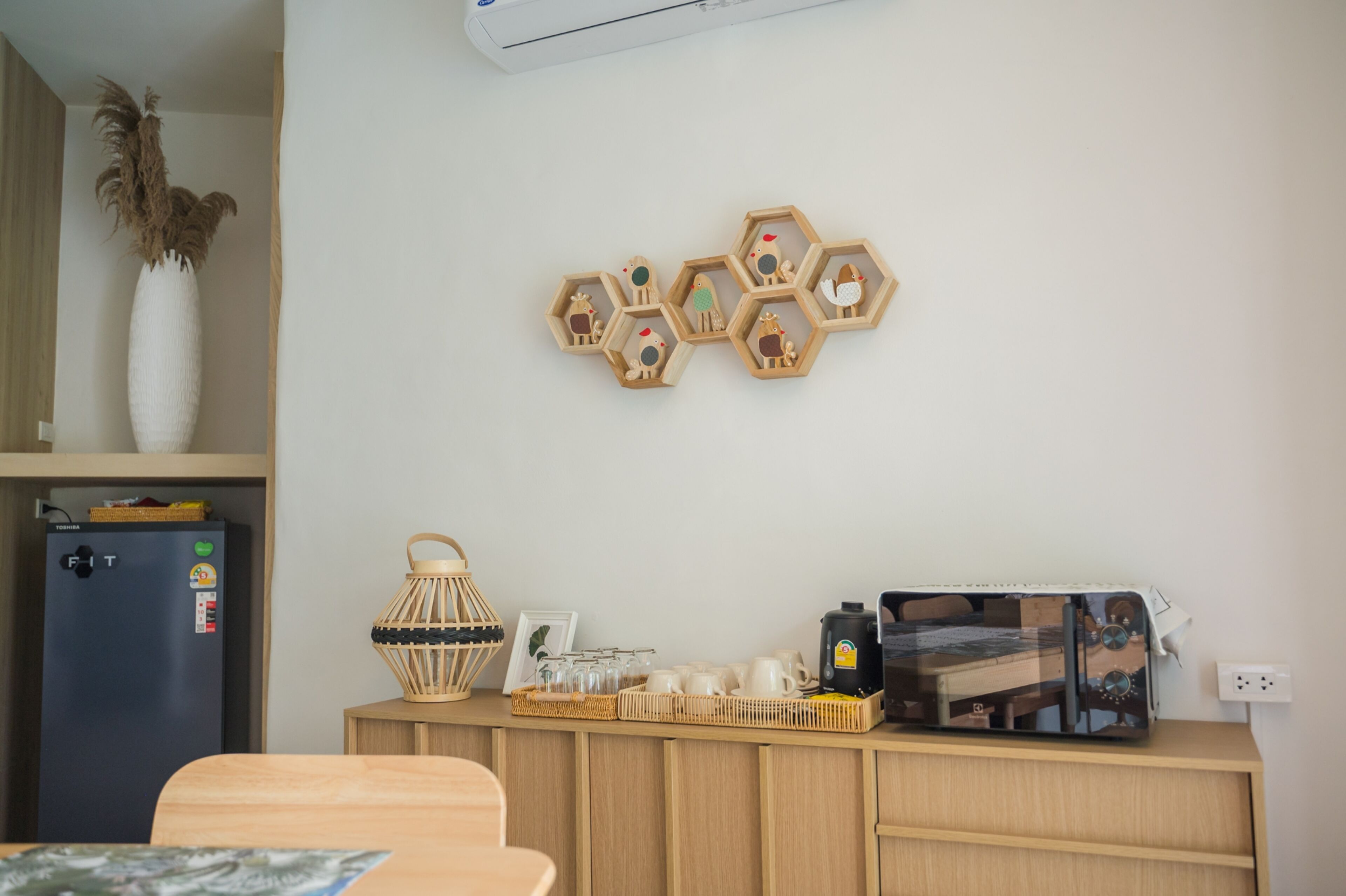 Un coin cuisine équipé d’un réfrigérateur, d’une machine à café et d’un meuble en bois contenant de l’ustensile de cuisine.