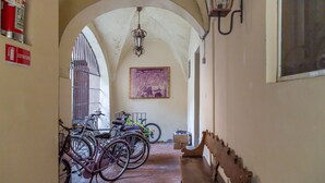 A corridor with bicycles parked, a fire extinguisher, and a bench. - VickyLù (Pavia)