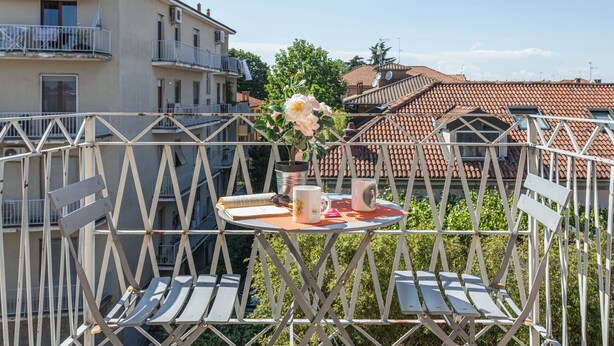 Un balcón con una mesa, sillas y una planta en maceta.